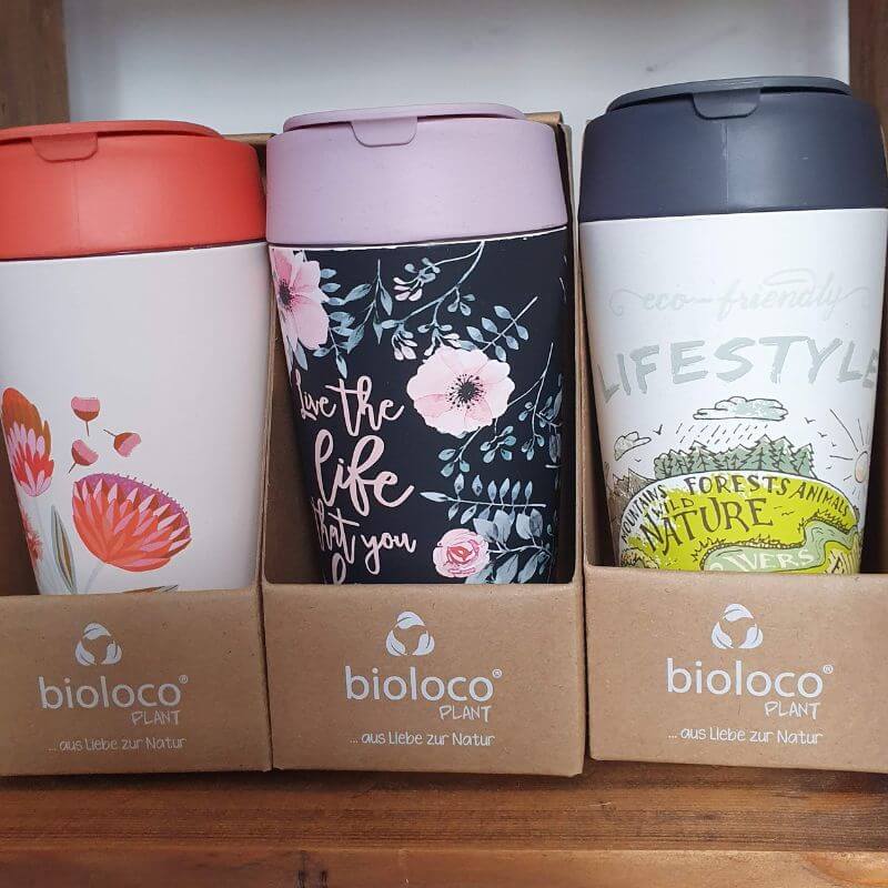 A set of three different designs of reusable bamboo coffee cups